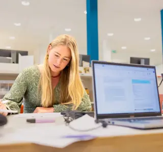 Jonge vrouw lang haar studerend in studiecentrum